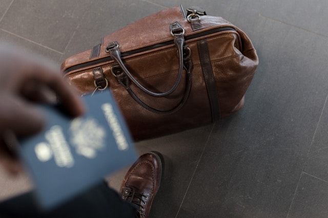 man carrying passport and travel bag
